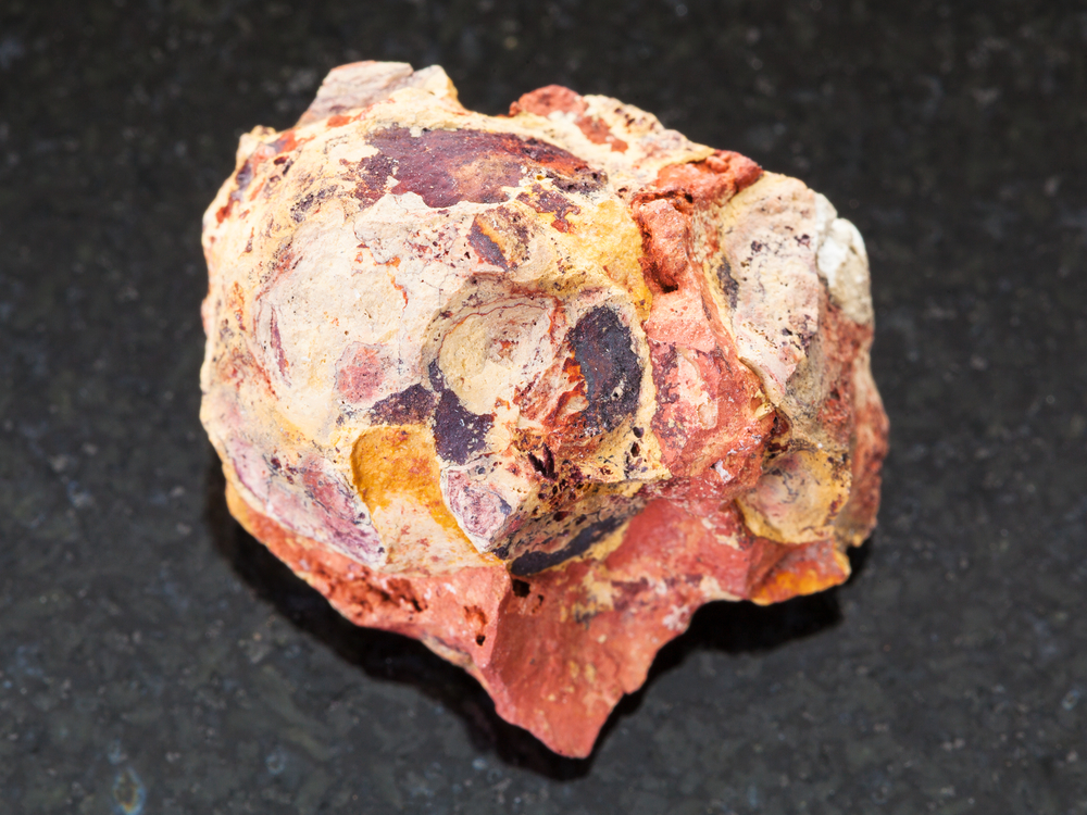 天然矿物岩石标本的宏观拍摄深色花岗岩背景上的未加工铝土矿铝矿石石